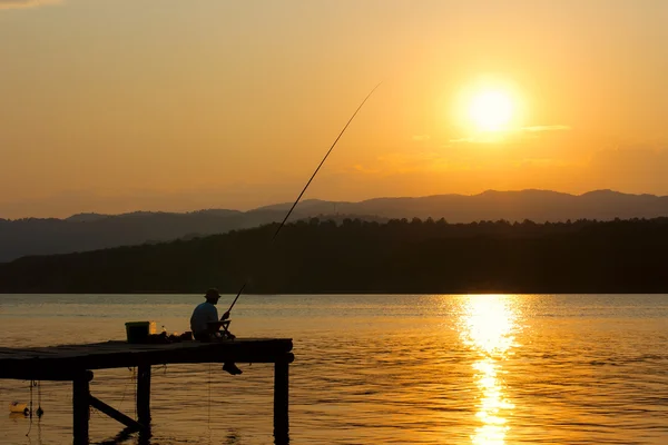 Рибалка на причалі на заході сонця — стокове фото