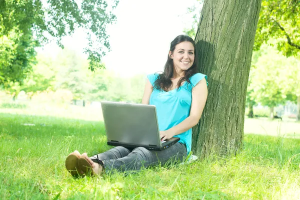 Heureuse jeune femme utilisant un ordinateur portable à l'extérieur — Photo