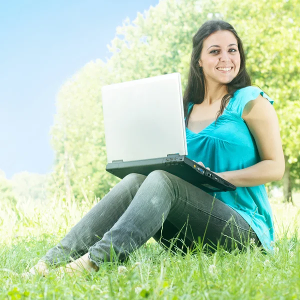 Щаслива молода жінка використовує ноутбук на відкритому повітрі — стокове фото