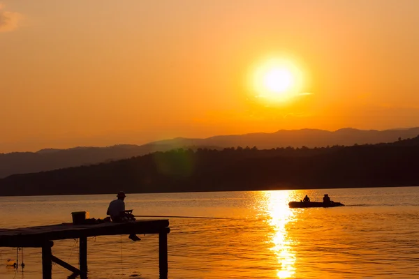 Рибалка на причалі на заході сонця — стокове фото