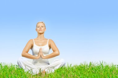 Young woman practicing yoga meditating outdoors clipart