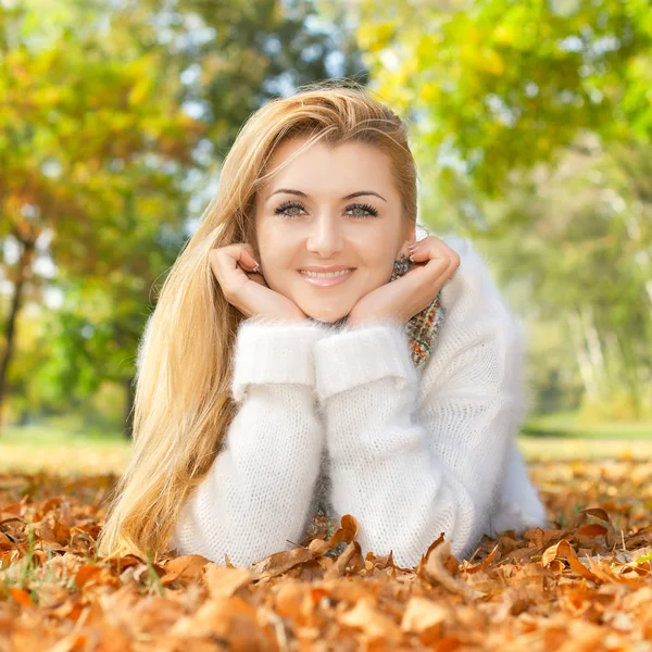 Donna sorridente sdraiata su foglie di autunno — Foto Stock