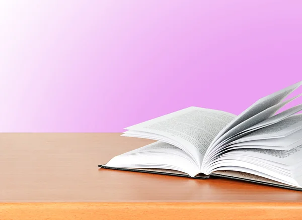 Livro aberto na mesa sobre fundo rosa — Fotografia de Stock