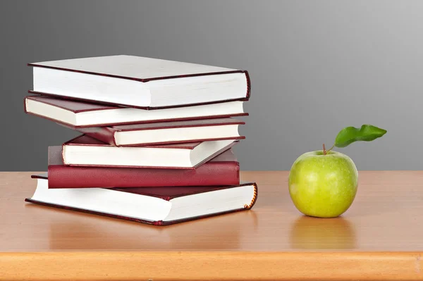 Zelené jablko a hromady knih — Stock fotografie