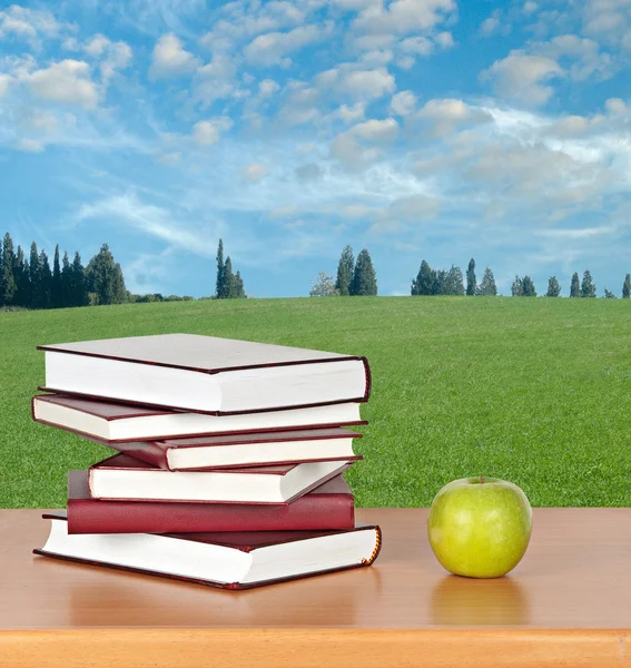 Bücher und grüner Apfel auf dem Schreibtisch — Stockfoto