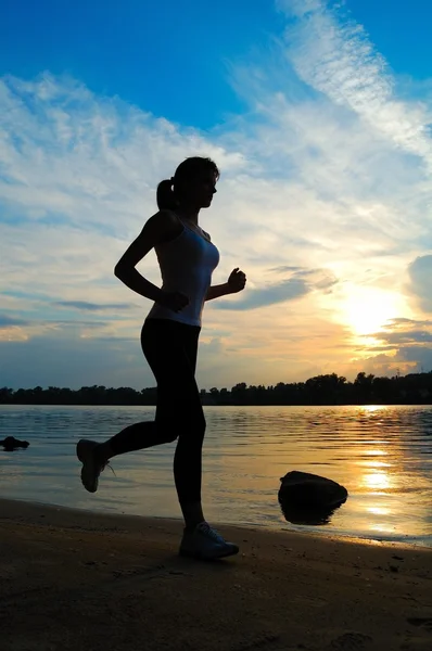 Σιλουέτα του όμορφη γυναίκα τρέχει στο ηλιοβασίλεμα — Φωτογραφία Αρχείου