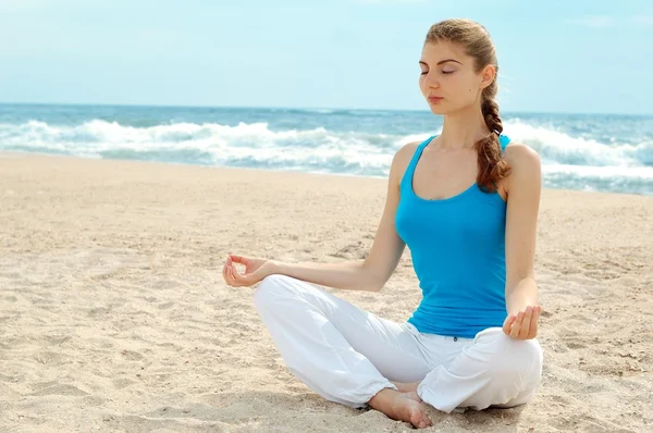 Красивая женщина практикует йогу на пляже — стоковое фото