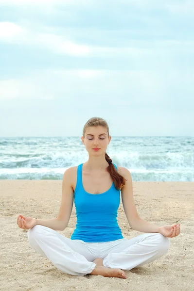 Красивая женщина практикует йогу на пляже — стоковое фото