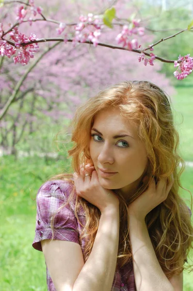 Red-haired woman under viloet flower tree — Stock Photo, Image