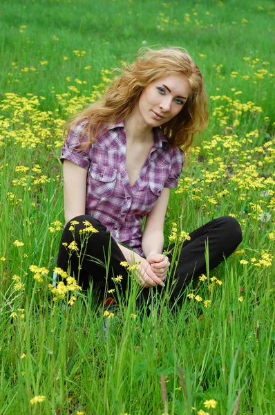 Sarı çiçekler arasında oturan kadın — Stok fotoğraf
