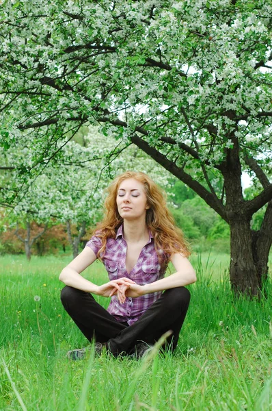 Woman meditating under blooming tree — Stock Photo, Image