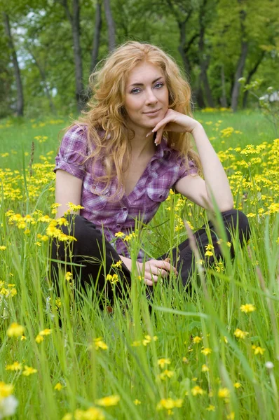 Sarı çiçekler arasında oturan kadın — Stok fotoğraf