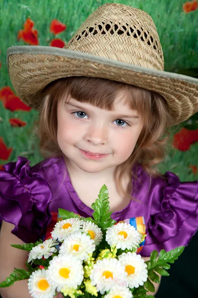 Jolie fille dans une robe violette et un chapeau de paille avec des fleurs — Photo