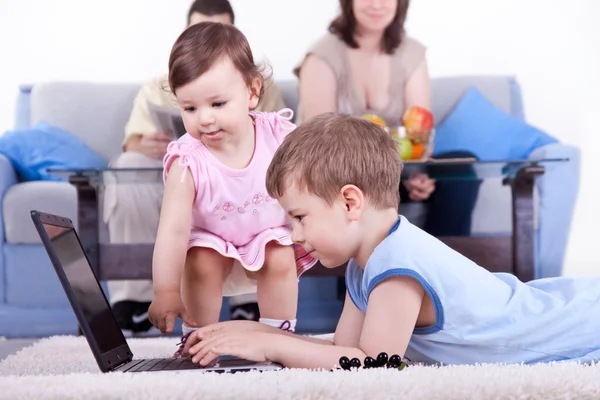 Pojke och baby flicka spela dator — Stockfoto