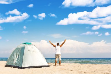 Man with tent enjoying camping on beach clipart