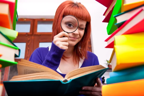 Tonåring med förstoringsglas och böcker — Stockfoto