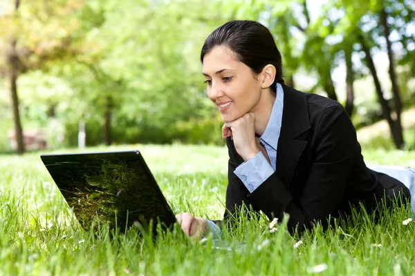 Geschäftsfrau liegt mit Laptop im Gras — Stockfoto