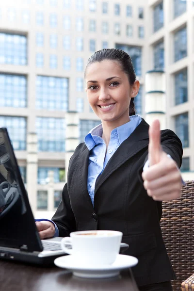 Business woman with thumbs up in restaurant — Stock Photo, Image