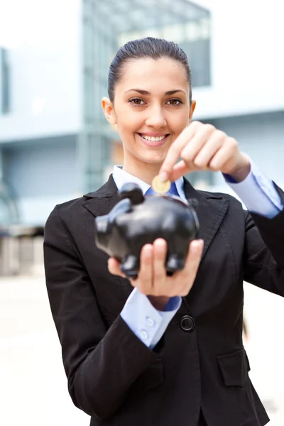 Affärskvinna att lägga mynt pengar i spargrisen — Stockfoto
