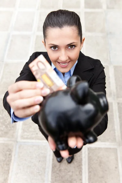 Zakenvrouw zet geld in spaarpot — Stockfoto
