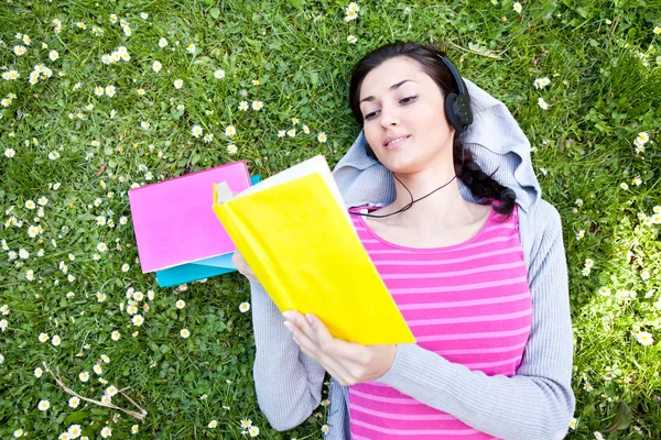 Mädchen liest Buch und hört Musik im Park — Stockfoto
