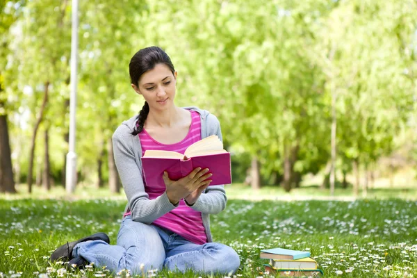 Красивая женщина в парке с книгой — стоковое фото