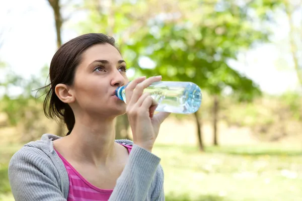 Дівчина п'є воду в парку — стокове фото