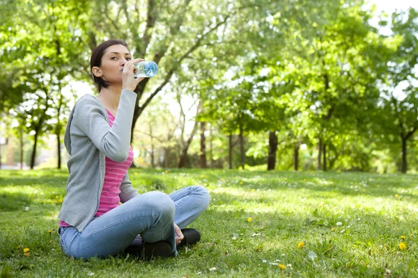 Mulher sedenta com garrafa de água — Fotografia de Stock