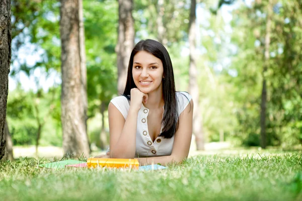 Usměvavá dívka s knihou v parku — Stock fotografie