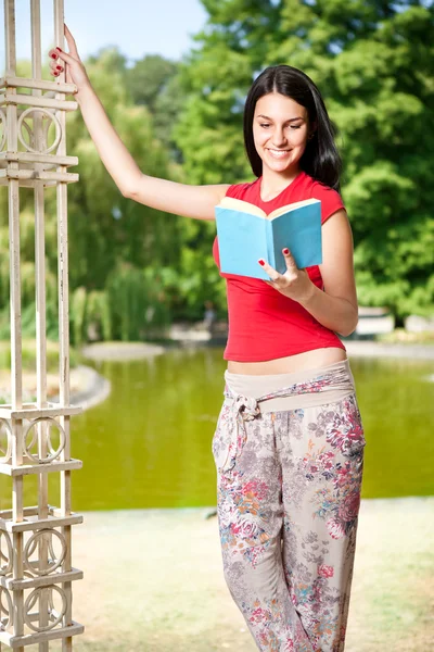 Student girl reading book in front lake — Stock Photo, Image
