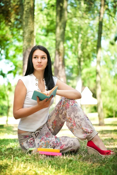 Denken meisje met boek in park — Stockfoto