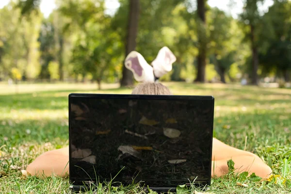 Jonge vrouw met laptop in park — Stockfoto