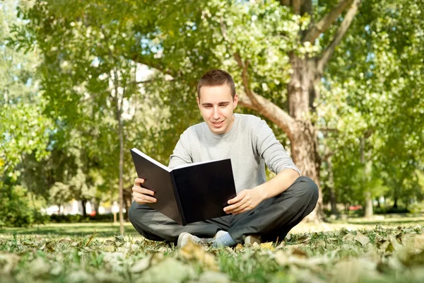 Student reading book in park — Stock Photo, Image