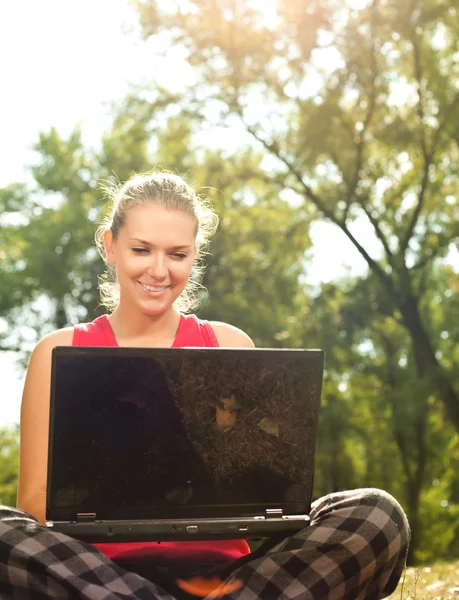 Frau sitzt mit Laptop im Park — Stockfoto