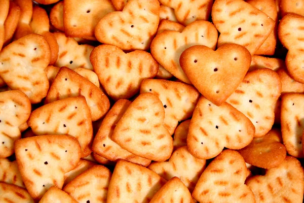 Heart made of a cracker on a background of others cookies 2 — Stock Photo, Image