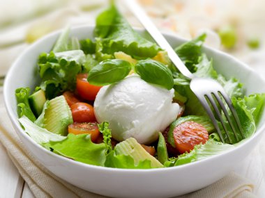 Whole mozzarella with green salad,tomatoes and avocado clipart