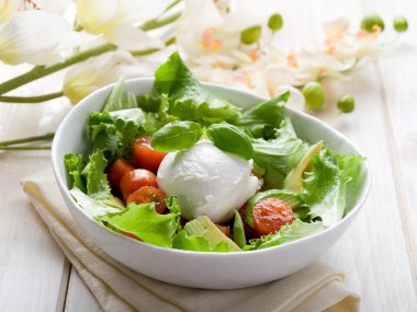 Whole mozzarella with green salad,tomatoes and avocado clipart