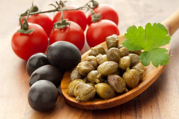 Kapris och svarta oliver över sked — Stockfoto