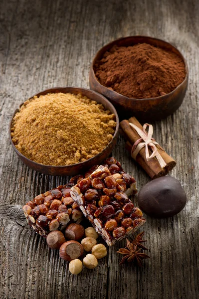 Hazelnut brittle on wood with ingredients — Stock Photo, Image