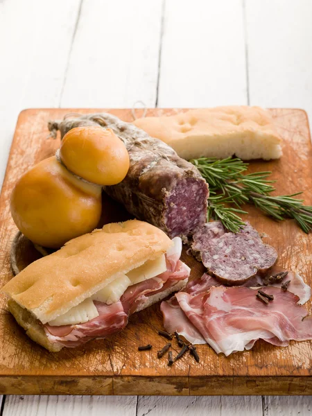 Focaccia with ham salami and cheese over cutting board — Stock Photo, Image