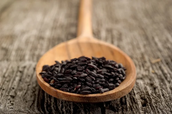 stock image Black rice on wood background