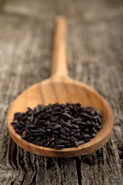 Schwarzer Reis auf Holz Hintergrund — Stockfoto