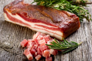 Slice bacon with rosemary on wood background