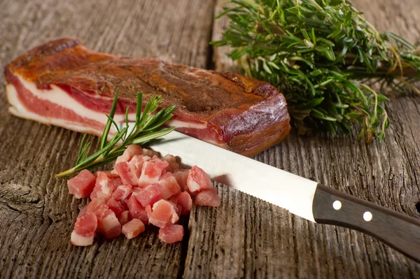 Slice bacon with knife on wood background — Stock Photo, Image