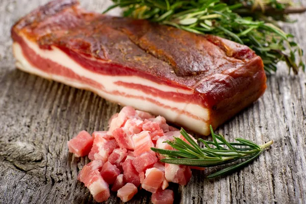 Slice bacon with rosemary on wood background — Stock Photo, Image