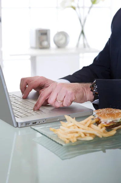 Manažer pracovat a jíst nezdravé jídlo — Stock fotografie