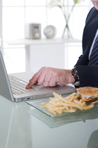 Manažer pracovat a jíst nezdravé jídlo — Stock fotografie