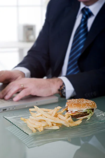 Gerente de trabajo y comer alimentos poco saludables —  Fotos de Stock