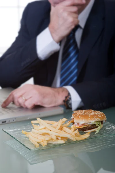 Gerente de trabalho e comer alimentos insalubres — Fotografia de Stock