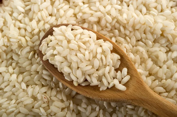 Rå ris över trä sked — Stockfoto